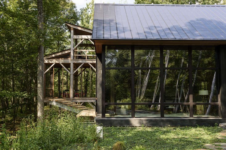 A three-story screened porch has a swing on the top level and a table and chairs for dining on the middle level. The sauna is at ground level at the bottom of a slope. Photograph by Reto Guntli, courtesy of BarlisWedlick Architects, from  Architect Visit: A Natural Pool and Passive House in New York&#8\2\17;s Hudson Valley.