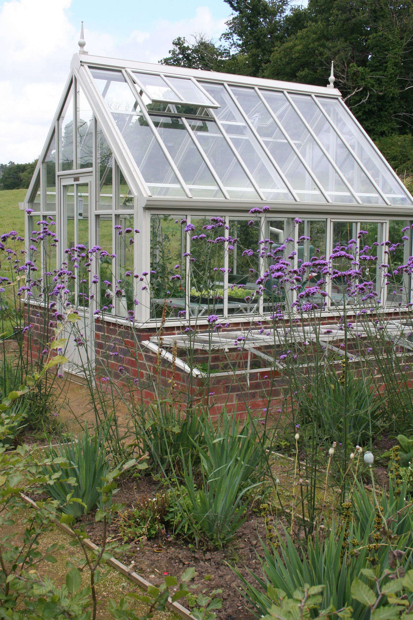 Historically, cold frames were built as greenhouse extensions tucked against the outer walls with southern exposure as seen (with their glass lids removed) outside Victorian glass houses. They offered a place to harden off seedlings on their journey from the cozy confines of the greenhouse to outdoor planting beds. Photograph courtesy of Annie Guilfoyle, from Before & After: A Kitchen Garden in Sussex, England.
