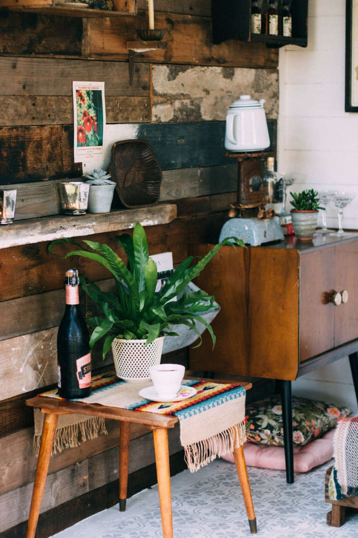 Vintage finds and spare cushions line one wall of the shed, which the couple covered in reclaimed wood.