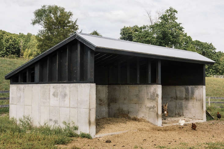 A poured-concrete shelter on the property is topped with cladding and framing that mimics the main barn.