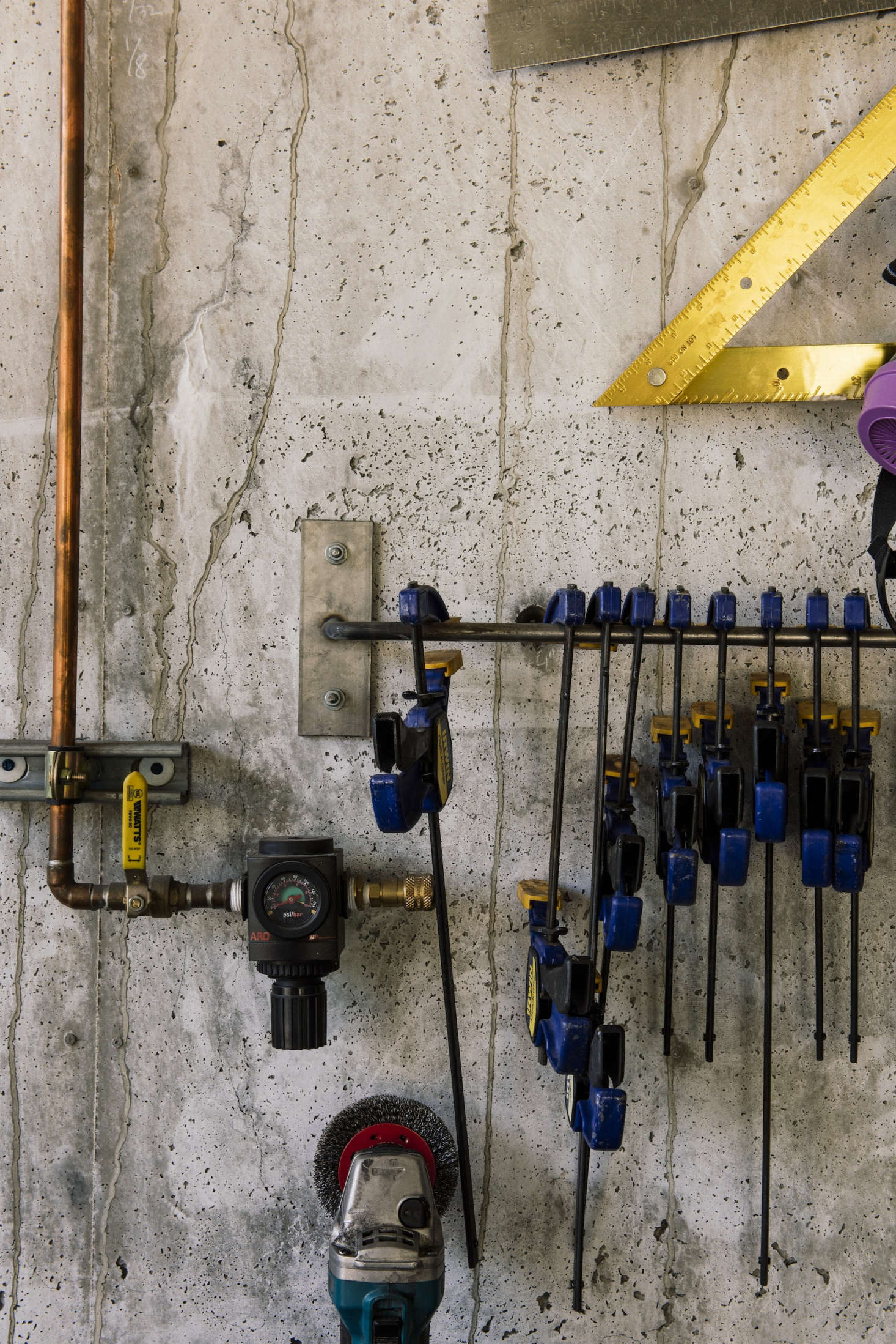 Steel hooks and bars keep shop tools like clamps and rulers in place. Exposed copper tubing is beautiful and necessary: It carries pressurized air for cleaning shop surfaces and materials.
