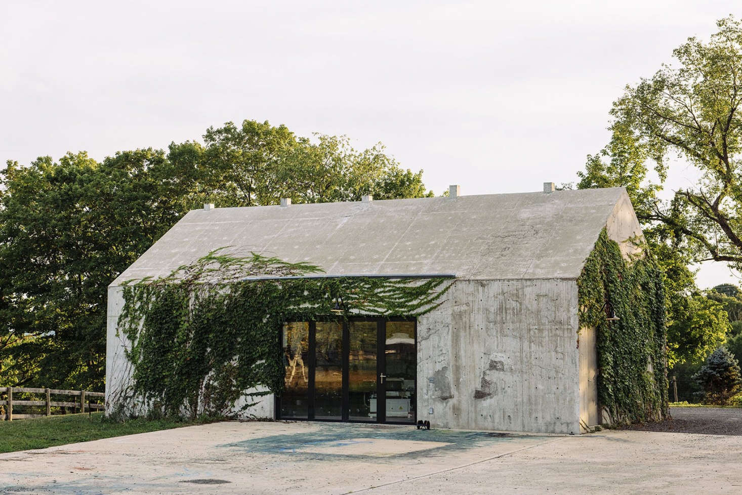 The welding studio is made of reinforced concrete, which first was poured to make three sides of the rectangular base (one side is glass), then poured inside a barn-roof-shaped form in one go.