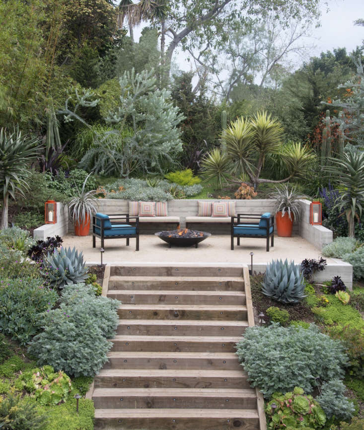 Built-in seating doubles as a retaining wall to create a sheltered spot for a fire pit in a Los Angeles garden.