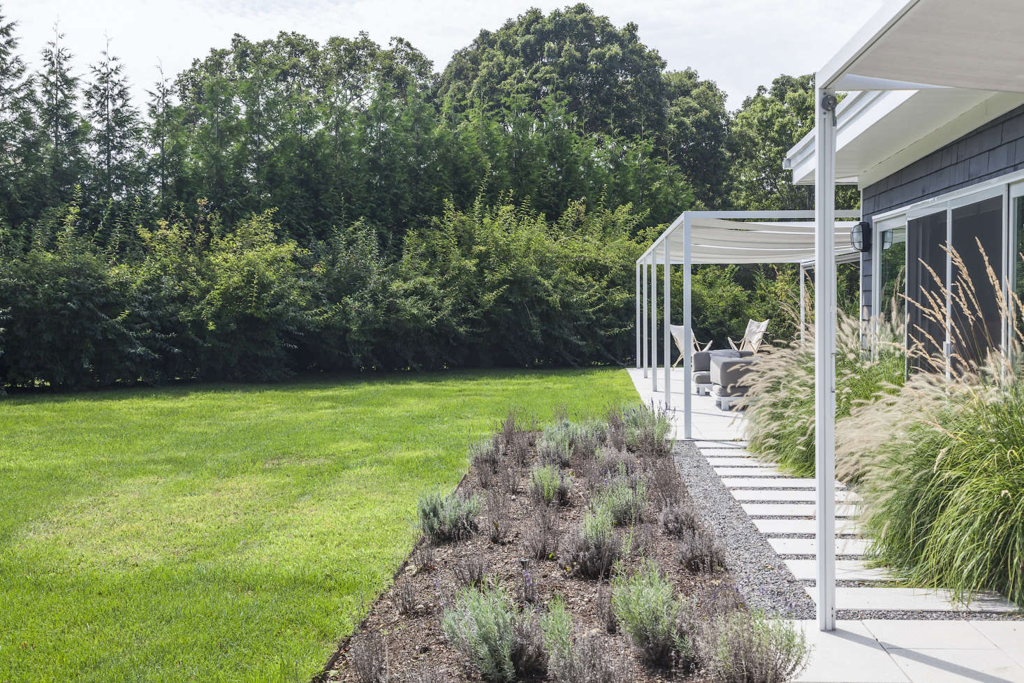 The kitchen and dining area are connected to the long veranda and pool lawn by a simple path of pavers and gravel.
