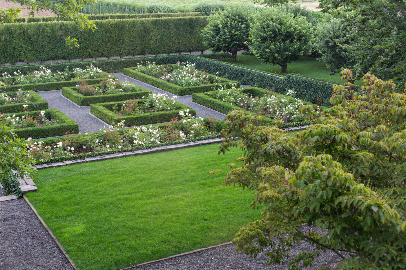 The walled rose garden, inspired by existing old roses, is laid out in a precise grid pattern. Dogwood trees (at R) soften the geometry of the sunken rose garden.