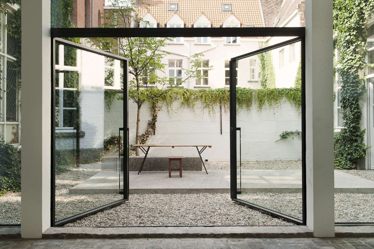 The courtyard in the Antwerp gallery-home of gallerist Veerle Wenes designed by Lens°Ass Architects features nothing but gravel, sparse vines, a single tree, and elevated concrete floor. Photograph courtesy of Verne, from Steal This Look: An Artful Gravel Garden in Antwerp.