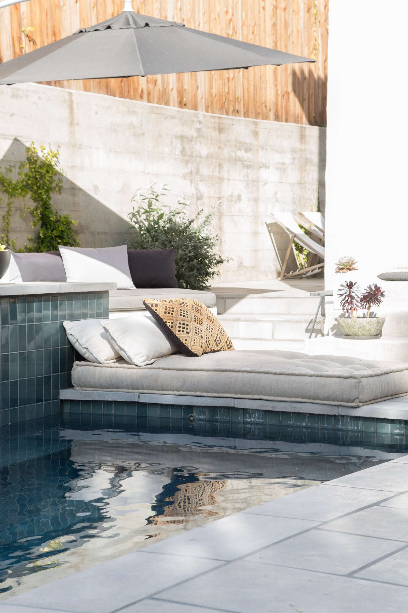 Another clever use of the hardscaping: A low cushion and pillows are positioned against the side of the pool to create a luxurious lounge spot, no furniture needed.