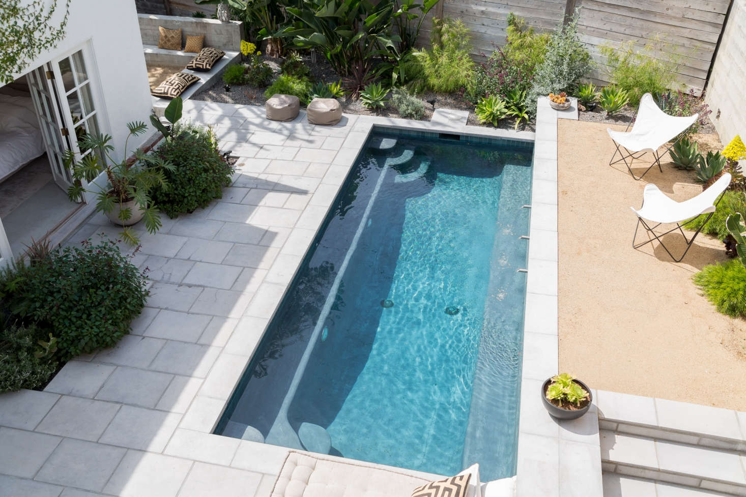 The main backyard area (counter-clockwise): pool, elevated gravel courtyard, garden, and sunken fire pit. The different levels make each space feel distinct.