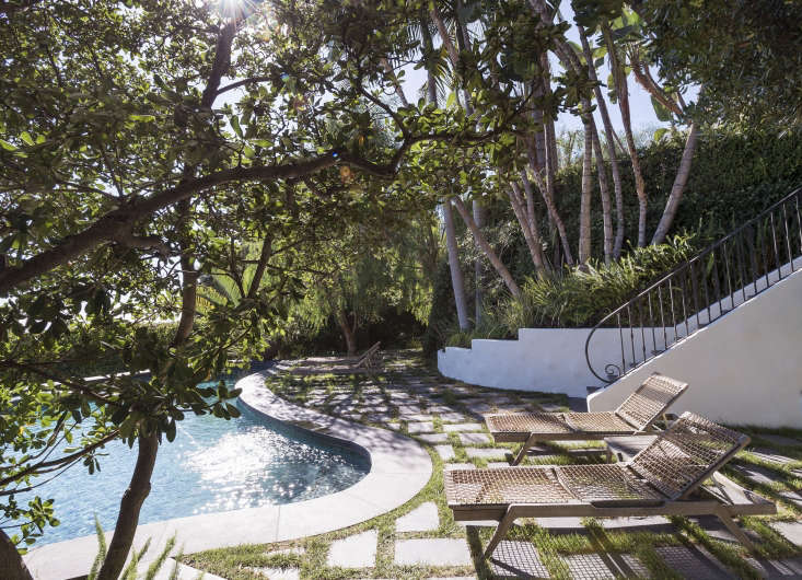 Black cantera stone pavers are set in a herringbone pattern and &#8\2\20;grouted&#8\2\2\1; with plugs of turf grass to create a permeable patio to surround a swimming pool in Los Angeles.