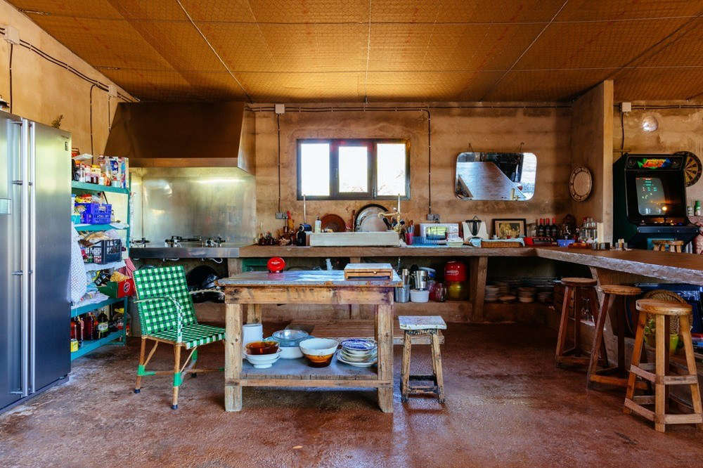 What had been the main sales room is now a cozy kitchen with a potting table as an island. The designers introduced a stainless-steel refrigerator and range, and put the existing wood counter and bins to good use.