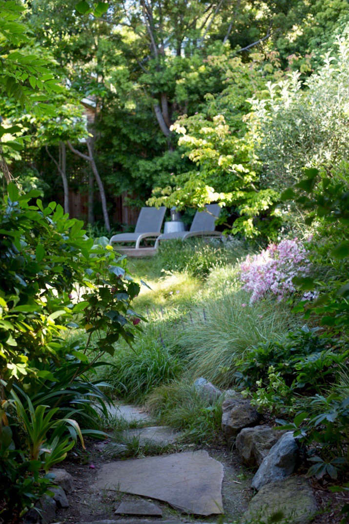 A path of stepping stones set in a base of gravel runs alongside the side of the house, connecting the front garden to the backyard meadow.