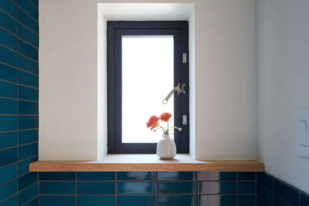 A Heath bud vase holds wildflowers on the bathroom window ledge.