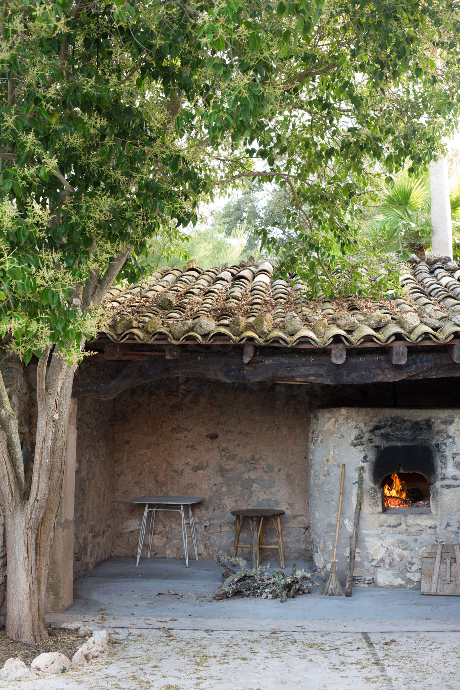 A wood-burning outdoor fireplace is adjacent to a shaded dining patio.