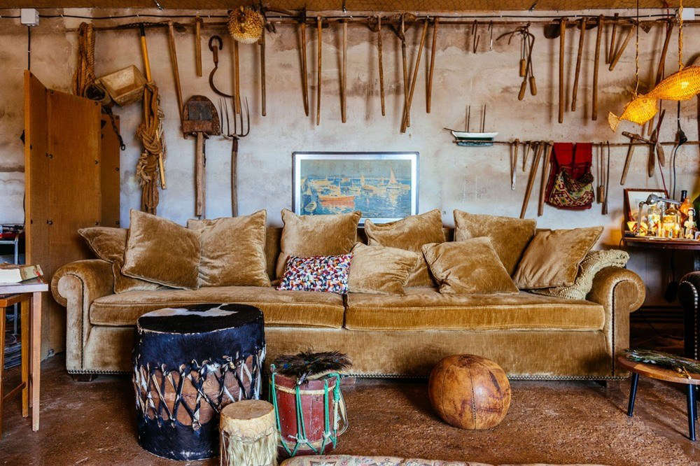 Left-behind garden tools hang from a metal rod in the living room, which is separated from the kitchen by a wooden folding screen. All of the rooms are linked railroad-style and open out to the deck.
