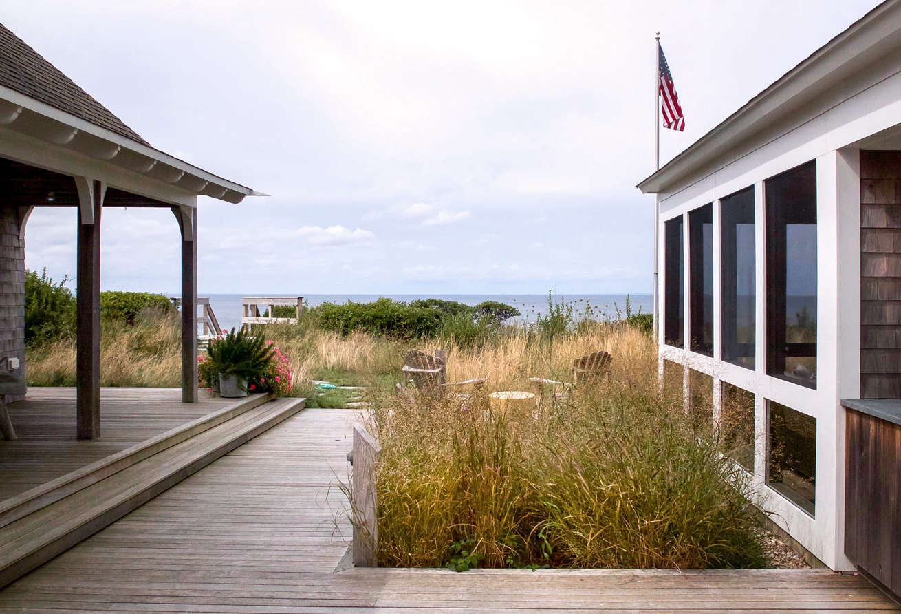The big reveal: beyond the front gardens, the house and grounds open up to take in the dramatic view. In this sheltered courtyard—flanked by the original cottage on the left, a newly built porch and the main house on the right, and another guest cottage at the back—Tim continued the grassy meadow with a small plot of Panicum virgatum 