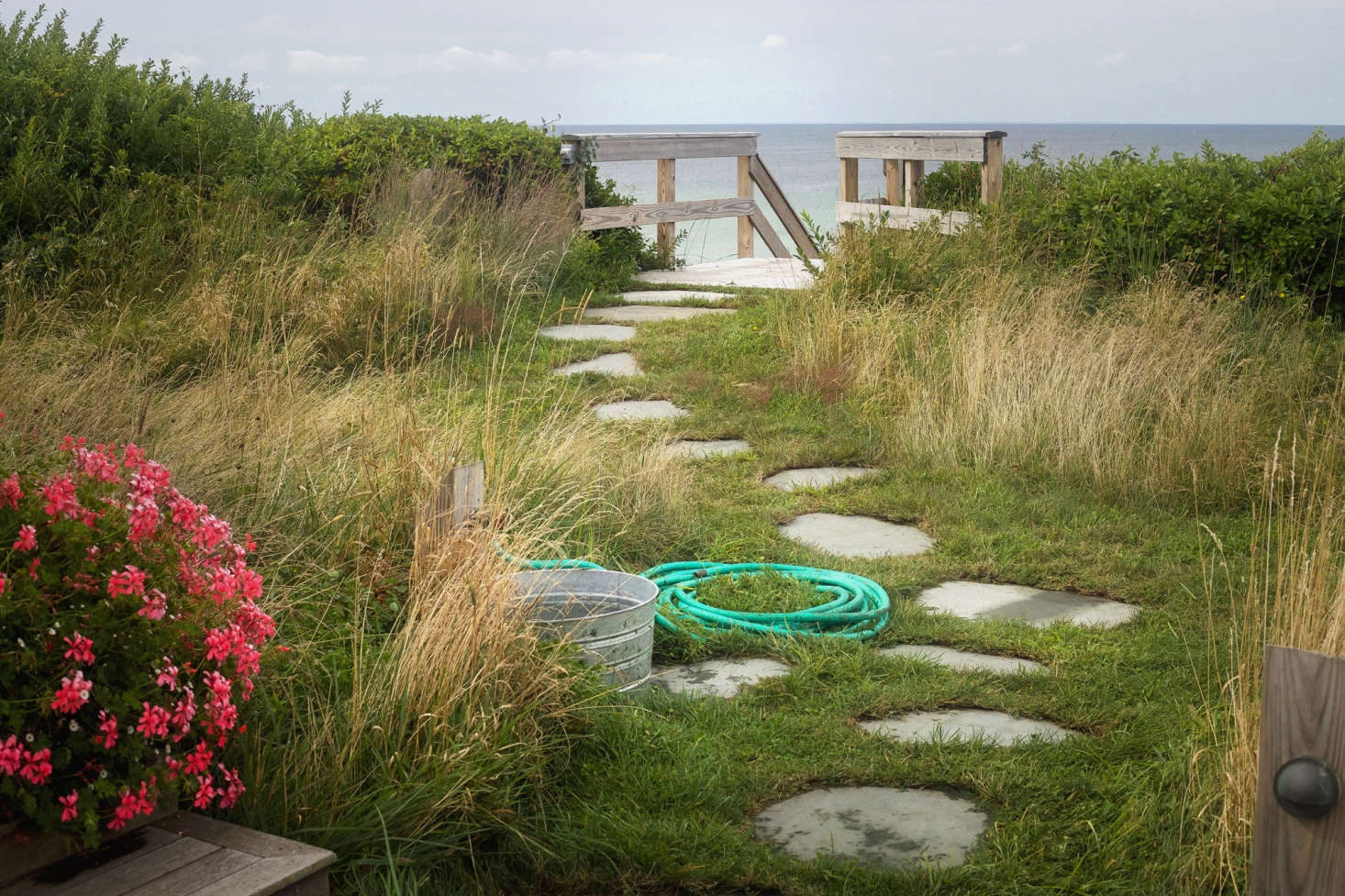 From the courtyard a traditional stone path leads to the steps down to the beach. One of our favorite informal elements is the simple hose and galvanized tube for washing sandy feet.