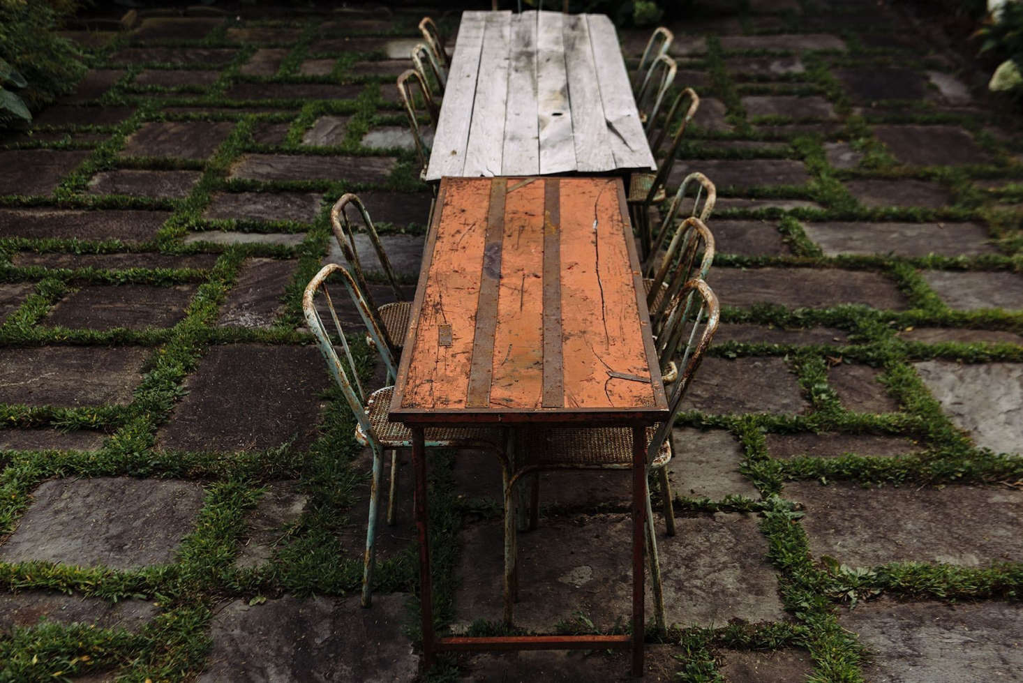 One-of-a-kind vintage dining tables sit end to end on the patio.