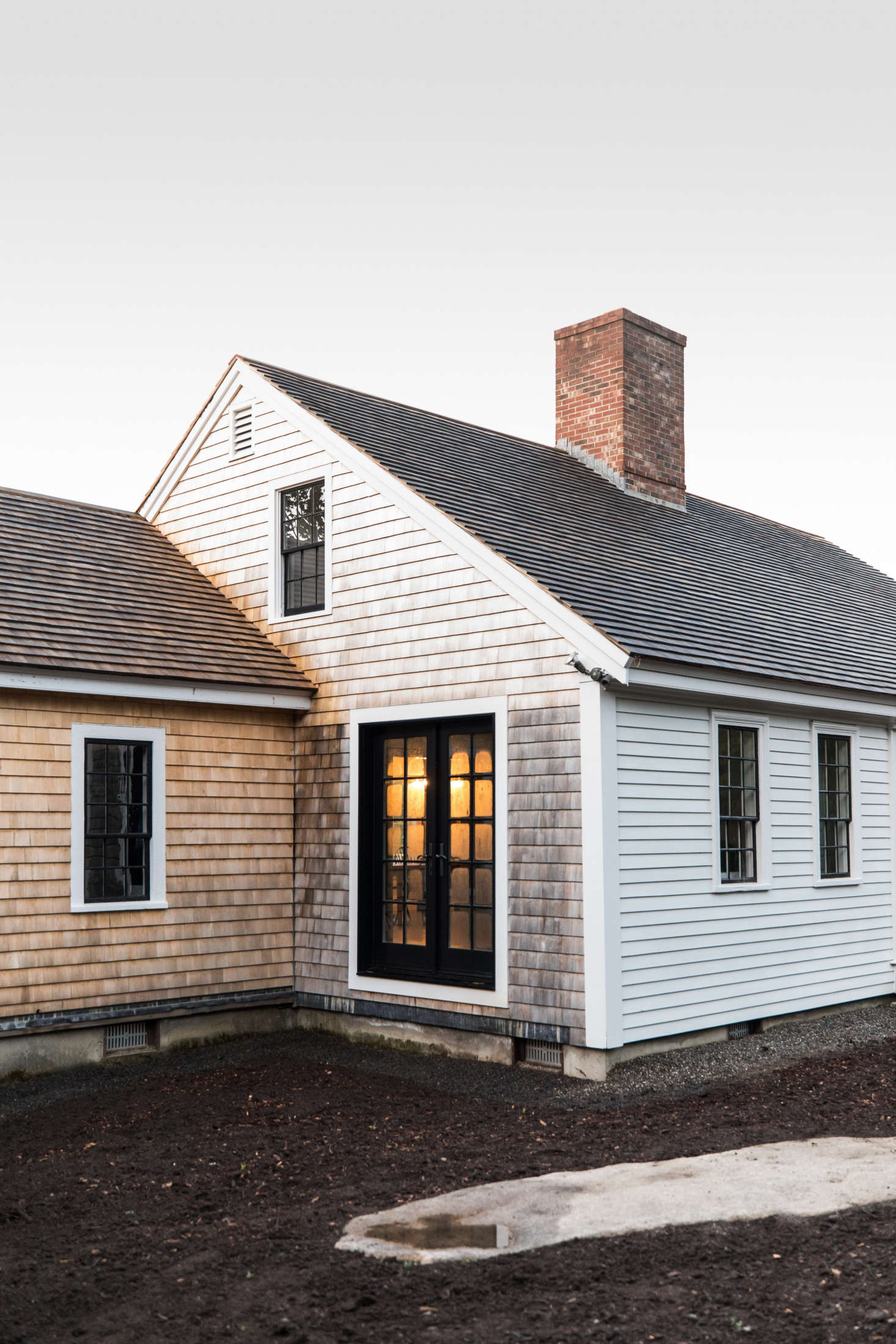 The front of the house is clad in traditional New England clapboards. The sides and small extension on the house are fitted with shingles that will weather. (Esteves is in the process of building a deck in this corner.)