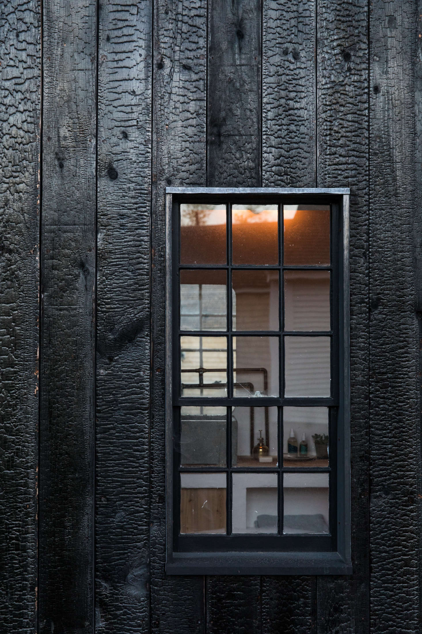 A detail of the charred-wood siding and windows with black mullions.
