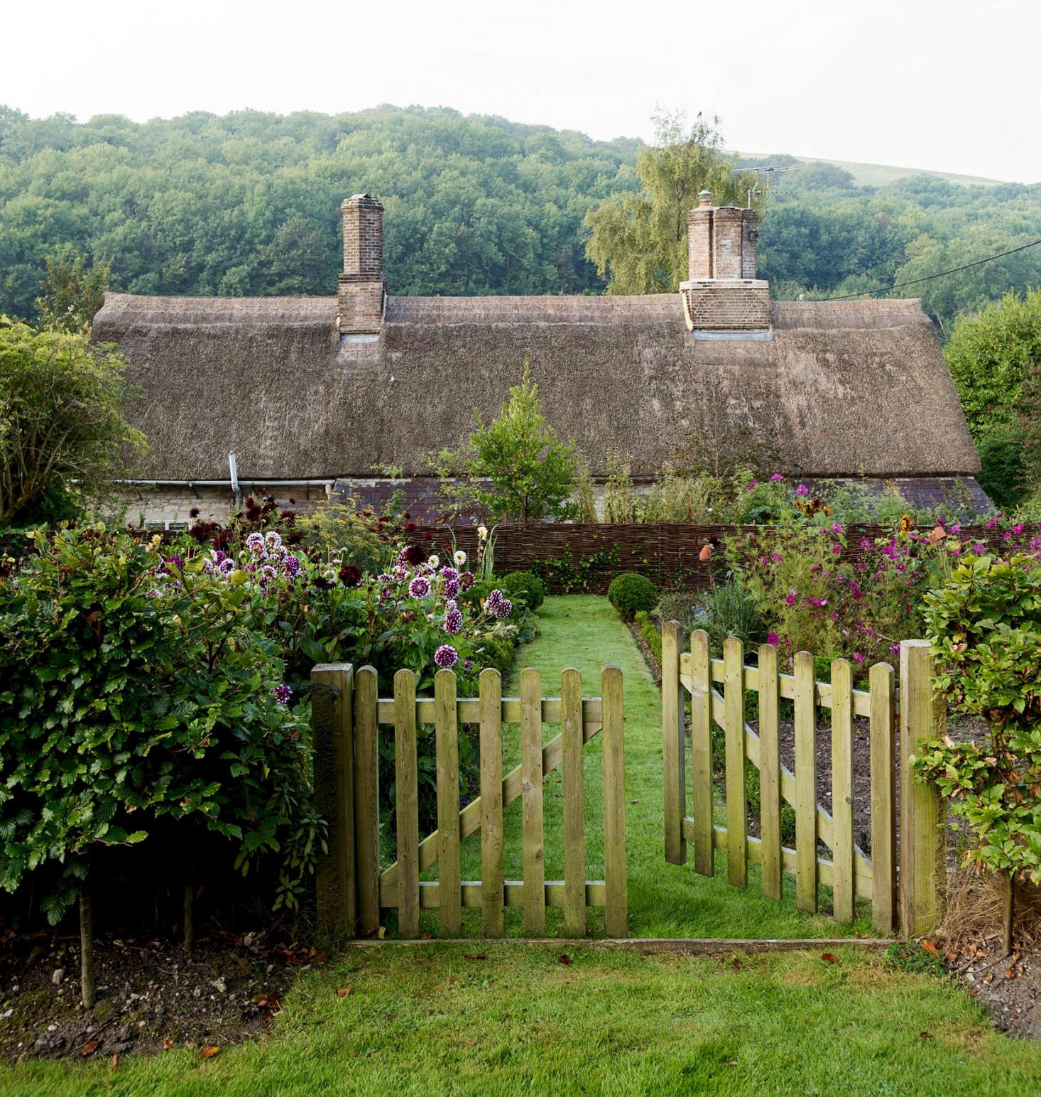 Architect Ben Pentreath uses fences and gates made of natural materials—including wood and woven willow panels—to create distinct boundaries in his garden.