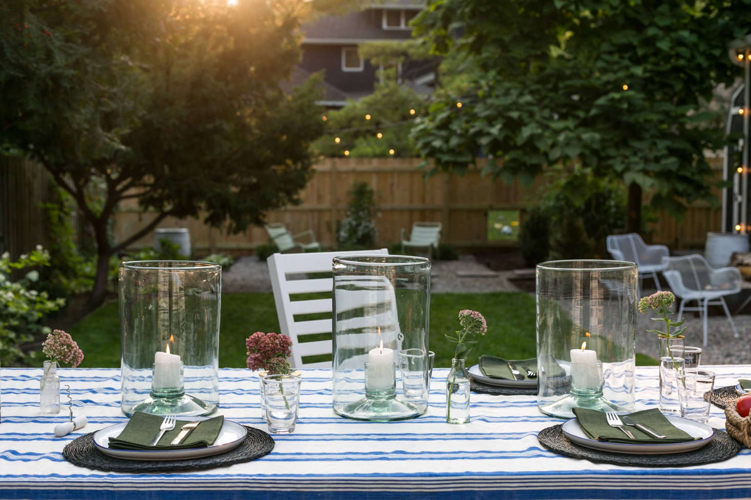 On the dining table are a trio of Lucia Recycled-Glass Hurricanes .