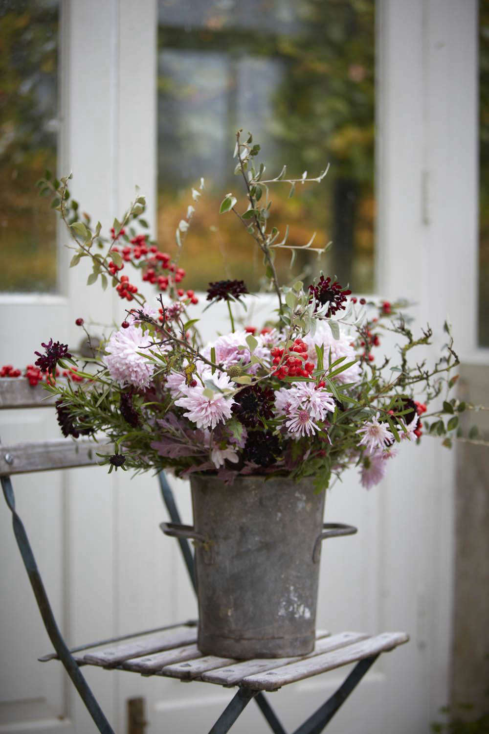 An early winter arrangement with red berries of cotoneaster, handfuls of rosemary, and dark scabious 