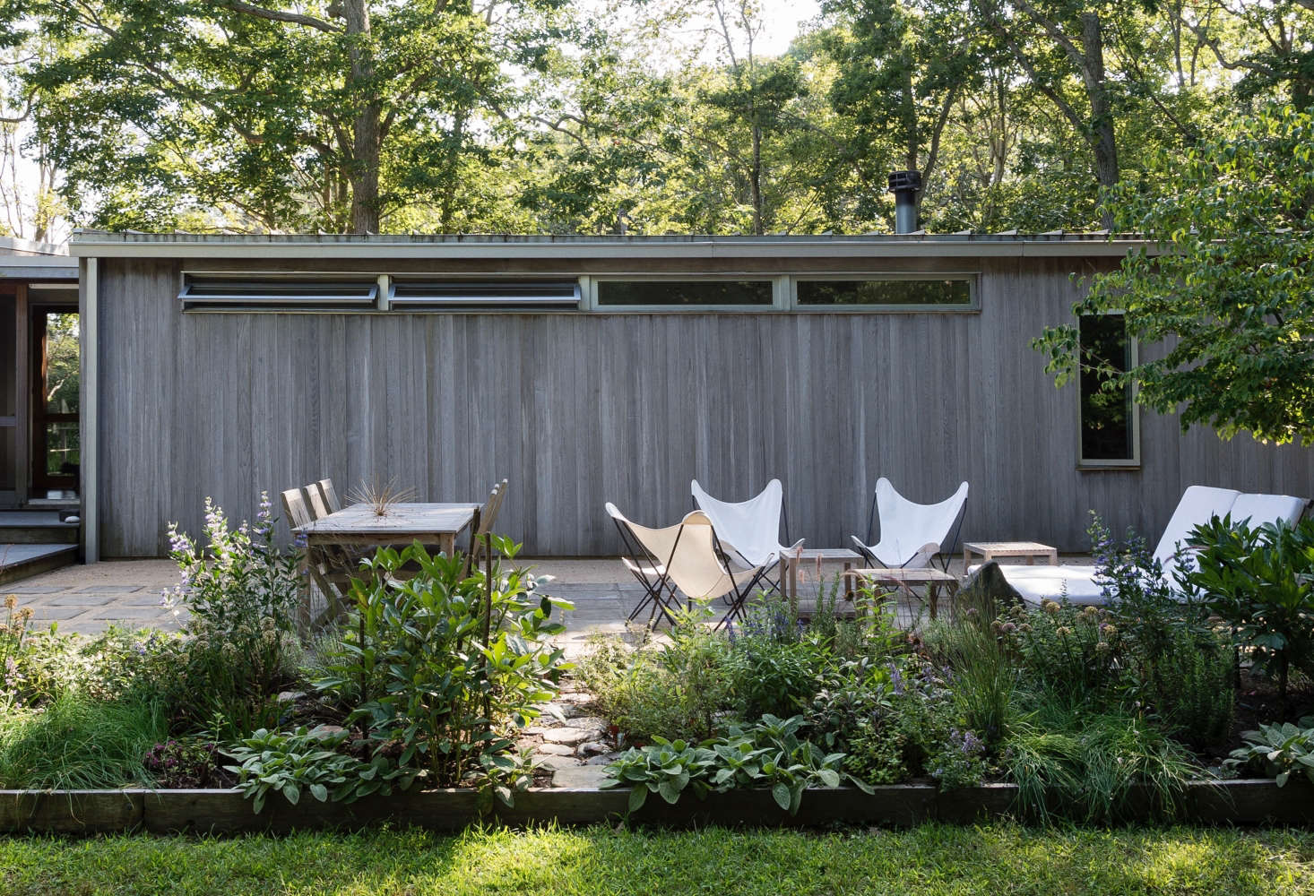 A simple patio adjacent to a house on Shelter Island, New York creates living and dining space outdoors.