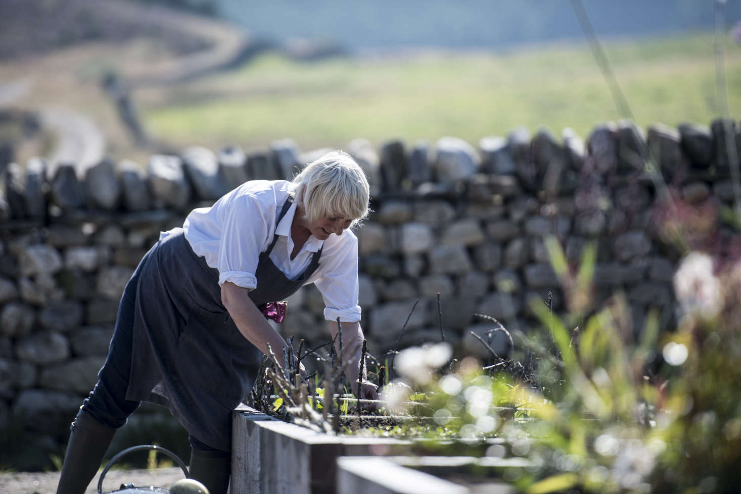 A farmer (fittingly, wearing wellies and a linen apron) tends to the vegetable patch.