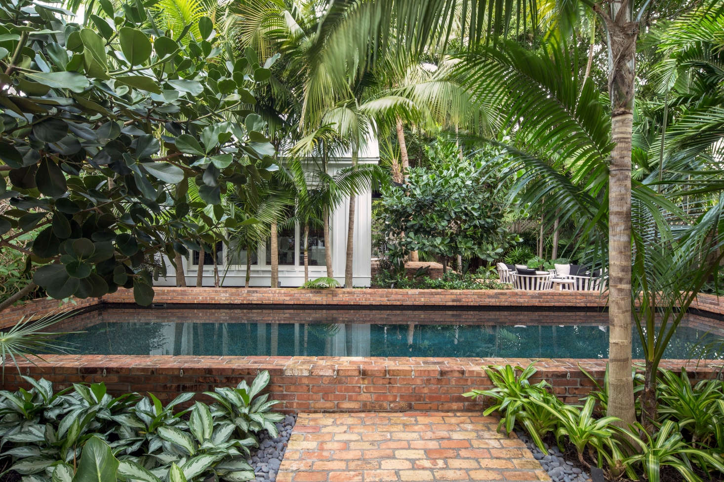 The running bond pattern on the front path continues into the backyard, where brick is used as coping on the raised lip of the lap pool, 