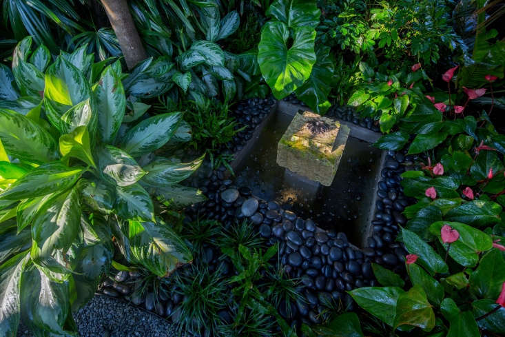 A water feature was sited to enable the owner to sit on the front porch and hear the sound of running water. Constructed of a square piece of oolite, as it ages the fountain will sprout ferns.