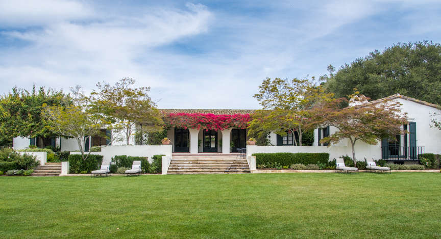 The grand lawn is kept simple, with a few chaise lounges and neat landscaping. 