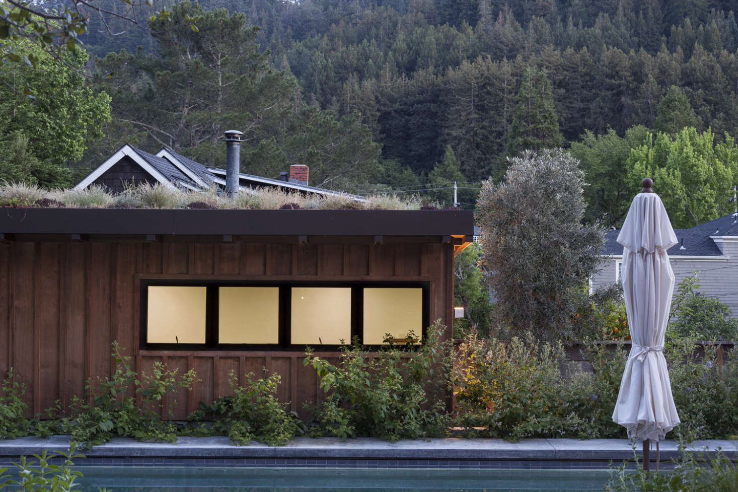 The new garage has stained board-and-batten siding to match the new wing of the house, and is planted with a green roof of drought-tolerant grasses and wildflowers.