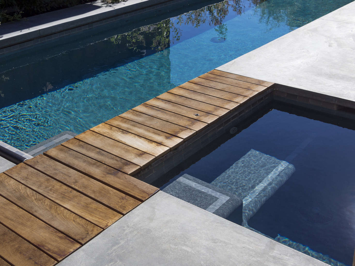 A water-resistant wood bridge crosses between the pool and hot tub.