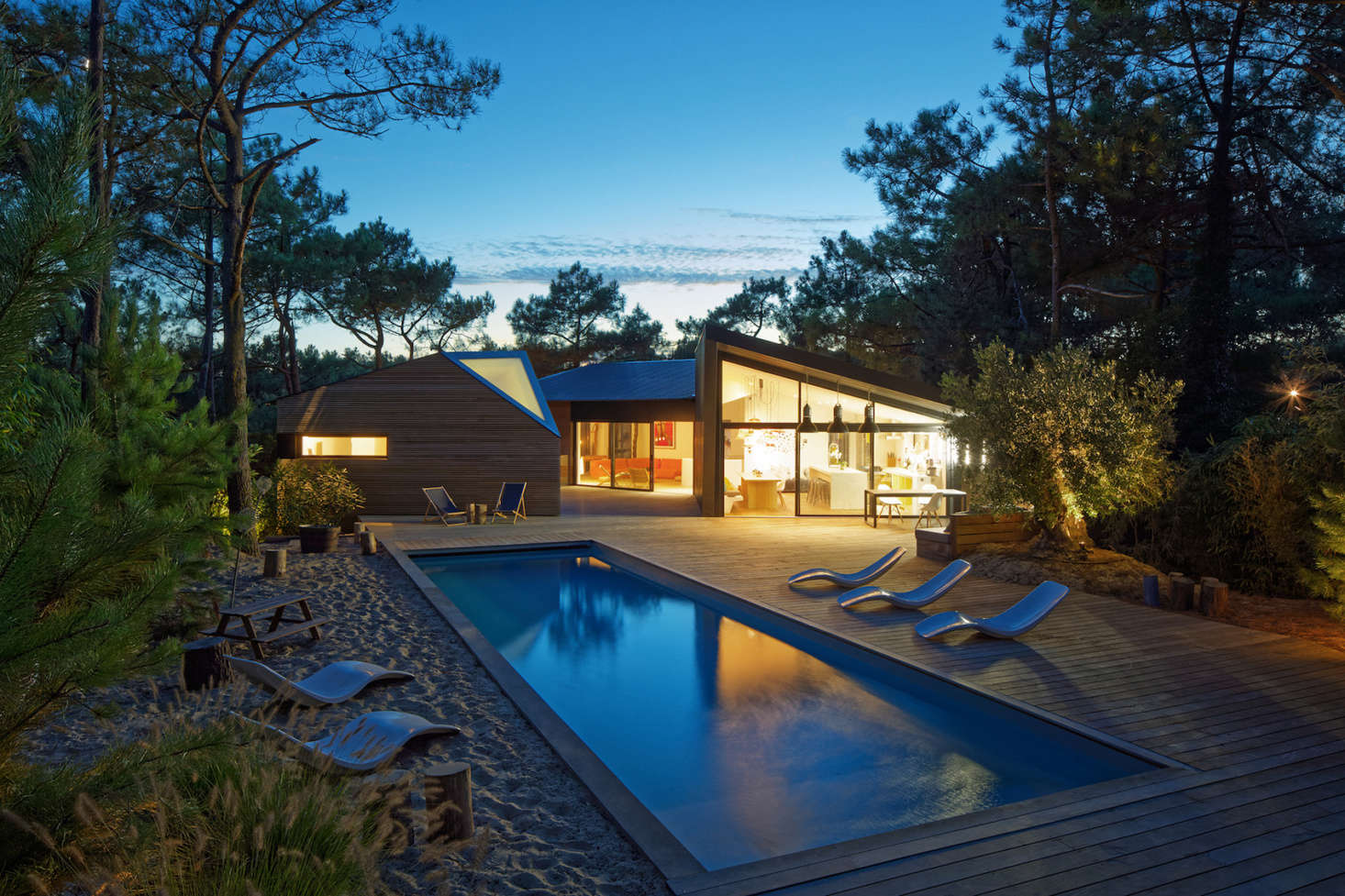 At night, a lantern-like glow from the house illuminates the pool and deck.
