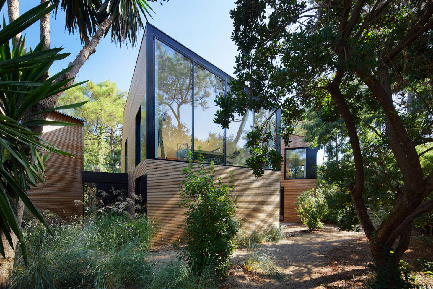 A large glass wall reflects ocean views onto a social space with playroom and pool table.