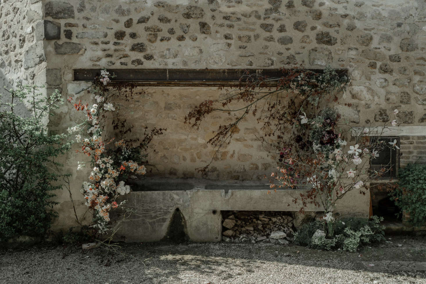 Blooms and branches climb up a stone wall at the country house.