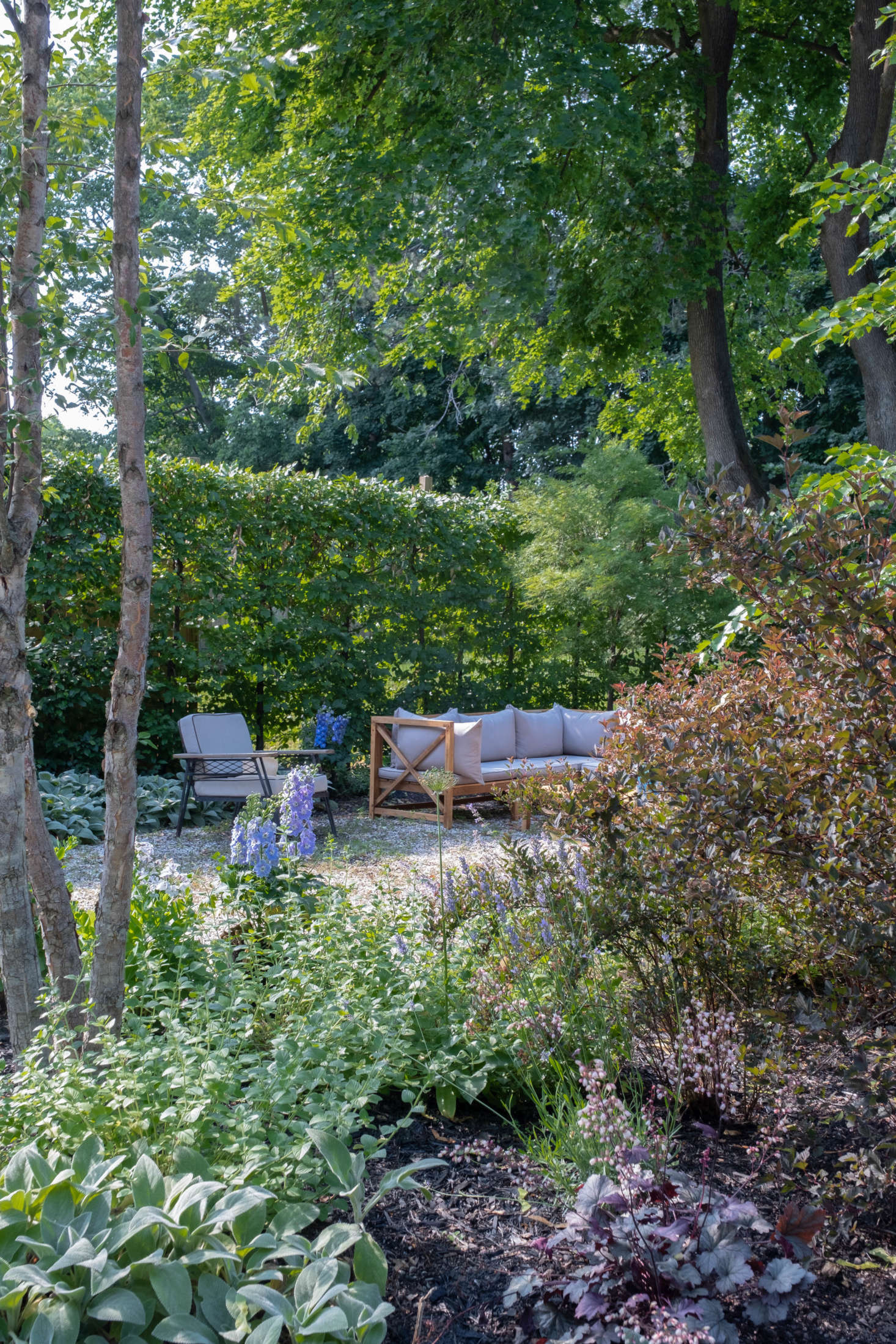 The garden beds curve and swoop to create privacy and separate spaces within the pea gravel patio.