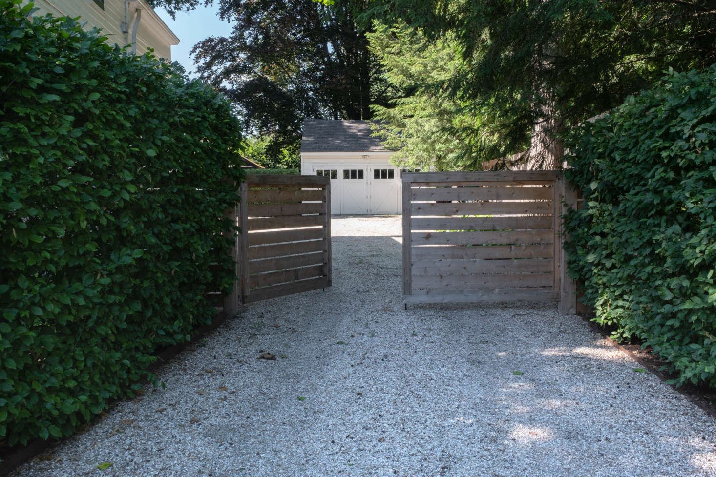 Just to the side of the house is a gravel driveway with the only addition the couple has made to the landscape: a swinging wooden gate that marks the entrance into the back gardens. 