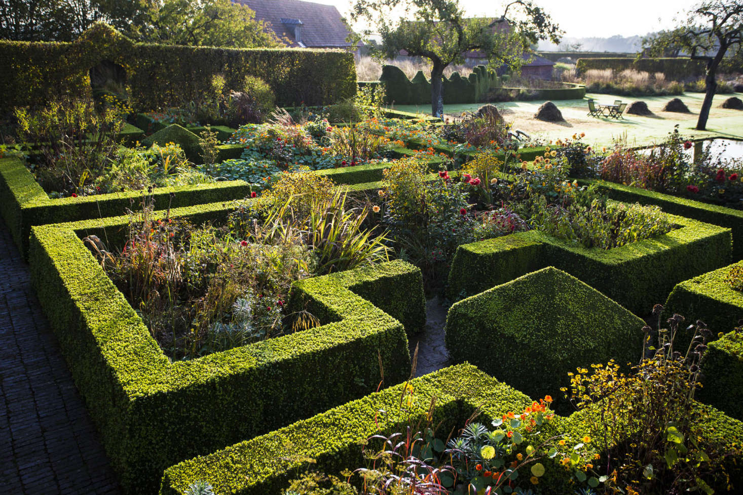 Sunset-colored plants clamber over the neat edges and corners of the formal parterre.