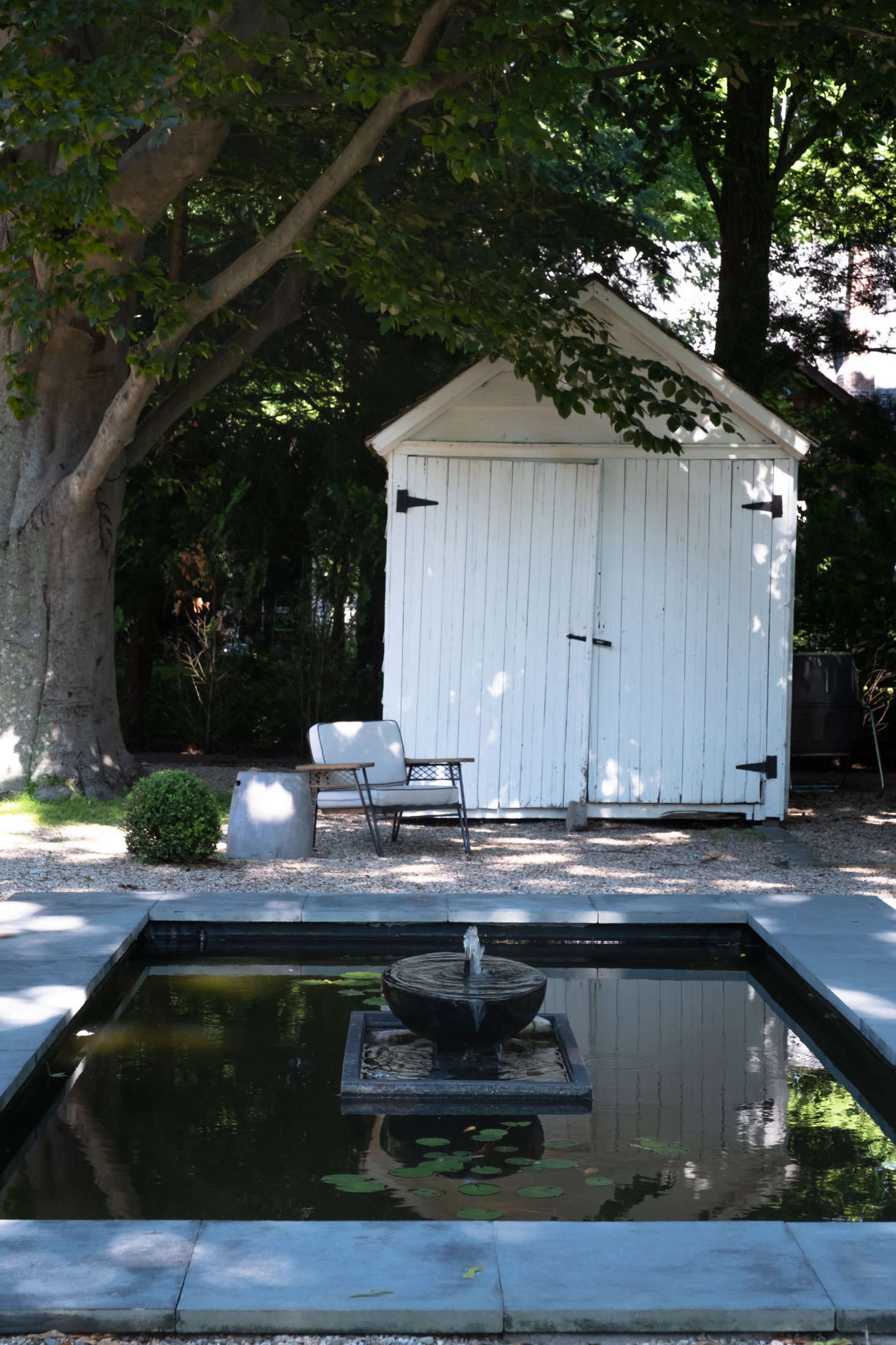 Despite its formal elements, the garden has a relaxed, languid feel to it, as though one could lounge all day eating strawberries in one of the vintage-style armchairs.