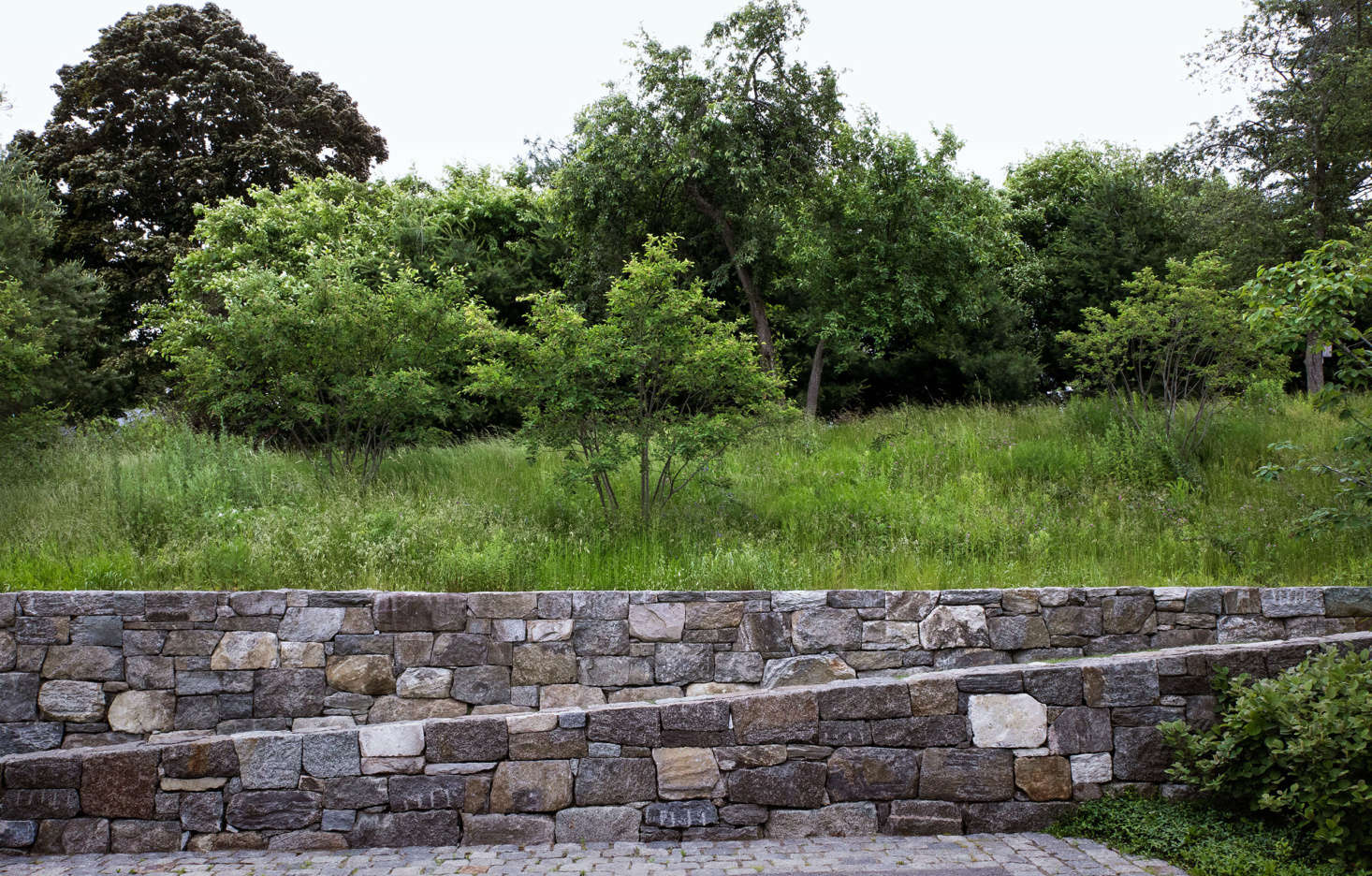 Bordered by the fieldstone ramp and lined with salvaged cobblestones, the generous entry court includes a basketball court, and doubles as a play area for children.