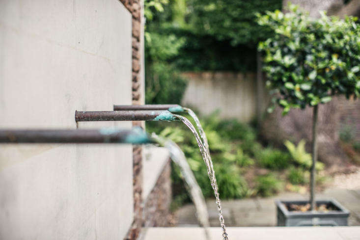 A row of antique copper spouts feed into the fountain.