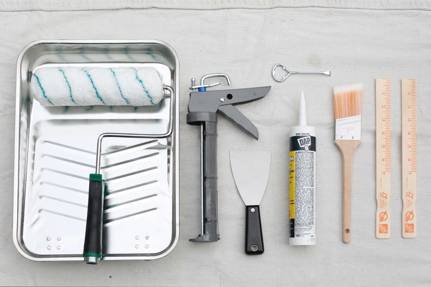 In the paint department at Home Depot, Michelle found supplies including a scraper, caulk, and a caulk gun, paint brushes, rollers, and pans.