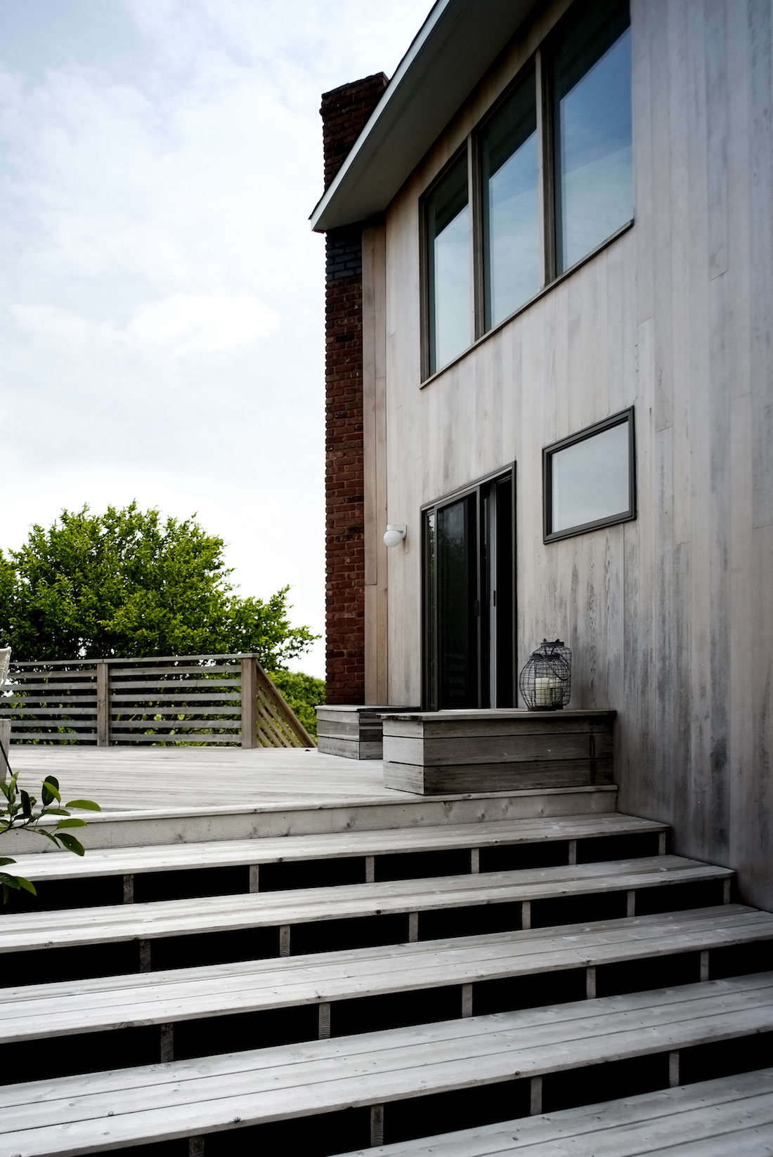 A simple palette for a beach house at the end of a rugged road on the tip of Long Island, New York includes a wooden deck with matching steps, abutting a cedar-sided facade. See more in Hardscaping data-src=