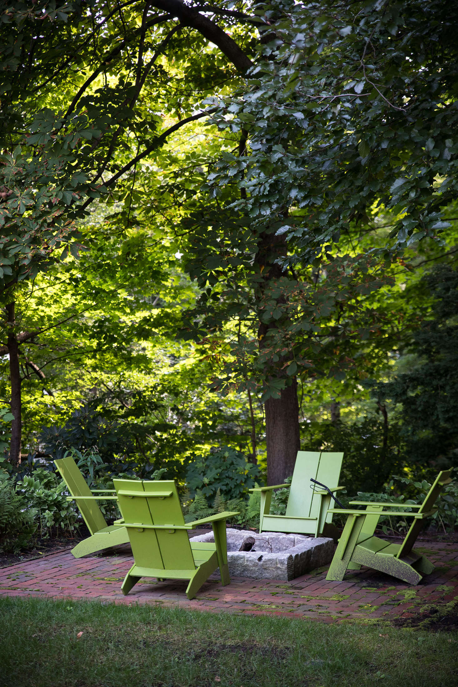 Tucked into a wooded area at the end of the great lawn, a fire pit constructed from reclaimed granite is surrounded by Loll