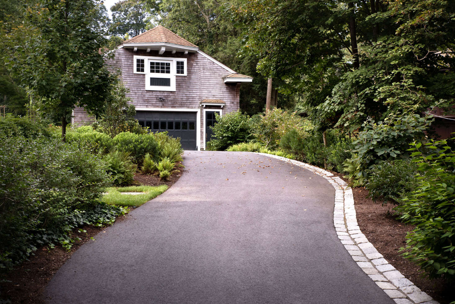 The driveway, which continues past the house to the historic garage, was completely regraded. A new cobblestone edge adds a historically inspired detail, and also channels storm water to prevent the site from flooding.