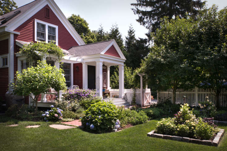 Surrounded by vine-covered pergolas, flowers trees, and perennial borders, the house seems to merge with the garden.