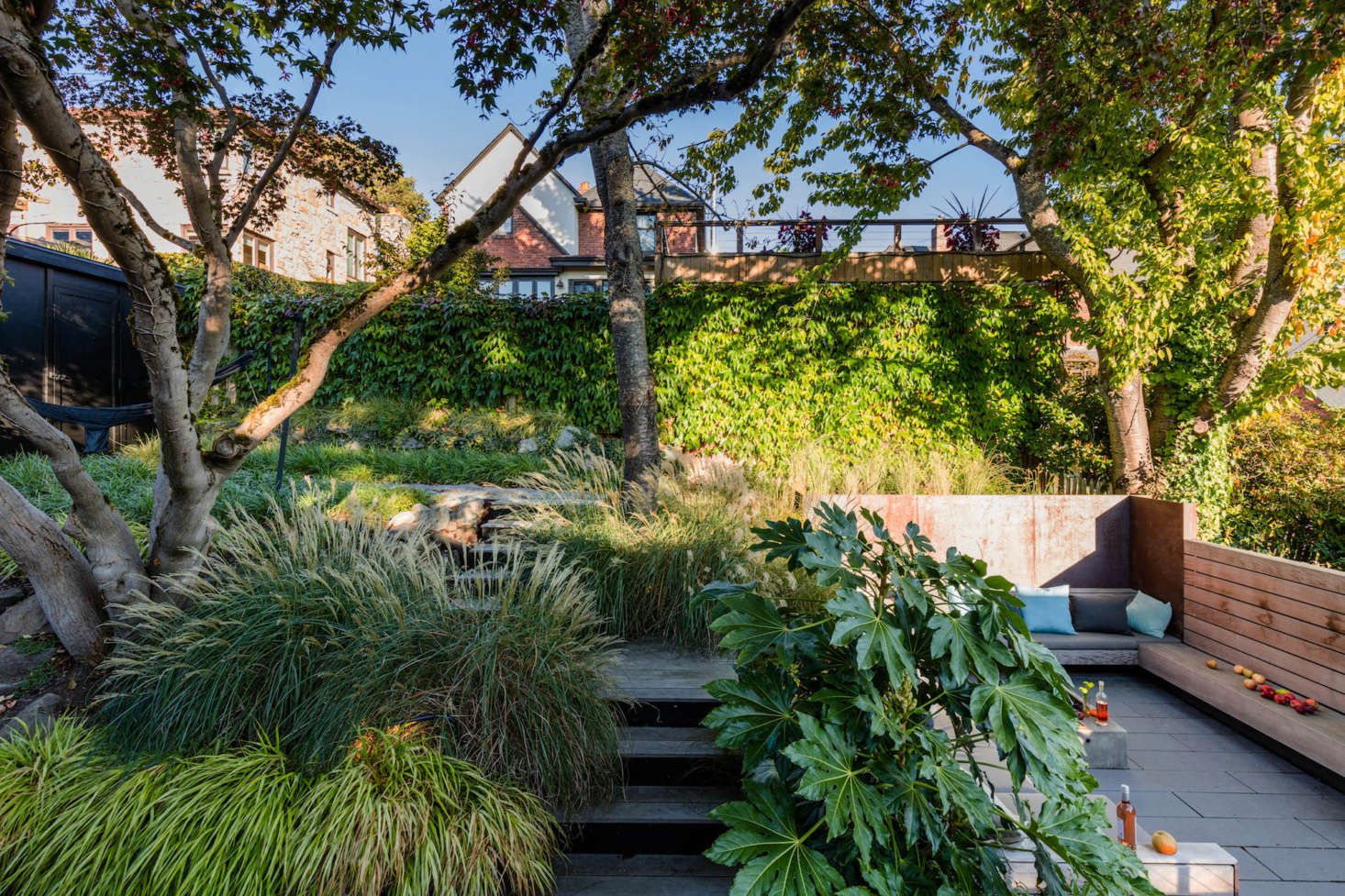 The multi-level lounge areas in the backyard provide ample opportunity to relax alone or host guests and include the deck, a hammock area (at left), and a sunken courtyard living room (at right),
