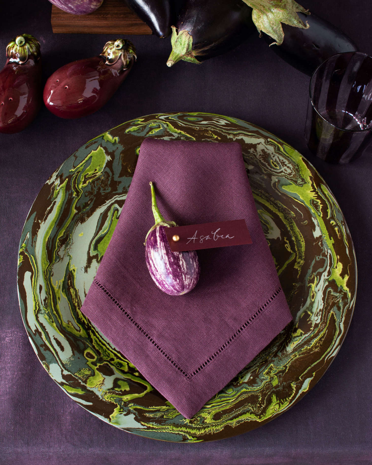 A mini eggplant makes for a perfect name card holder. The napkin, in raisin, is from SFERRA.com; the plate is from Atelier Saint André Perrin.
