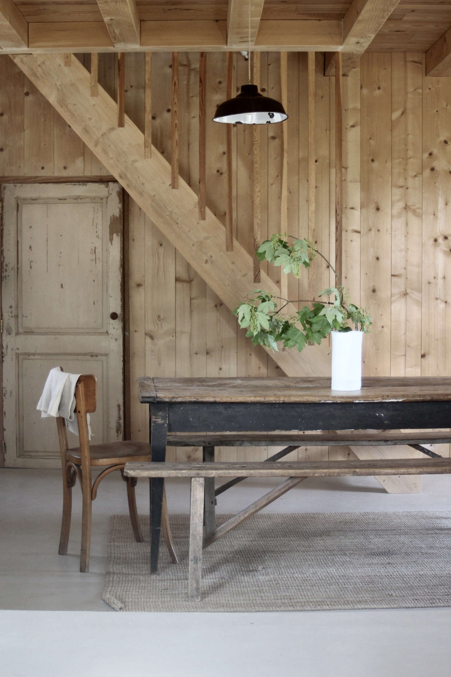 In a minimalist-rustic cabin in France, a branch of foliage offers just the right amount of color. Photograph by Jean Hay de Slade, courtesy of Epure, from Creative Compound: A Ceramic Artist Couple at Home and Work in the French Countryside.